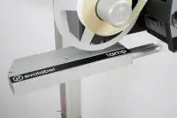 Close-up of an Evolabel labeling machine with a beige label roll mounted, ready to apply labels to products.